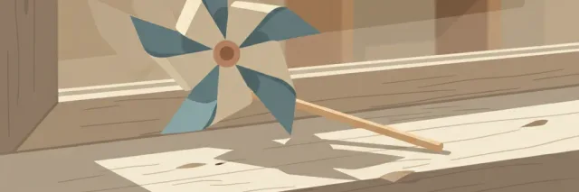 A simple paper pinwheel in muted blue and cream resting on a windowsill, soft afternoon light